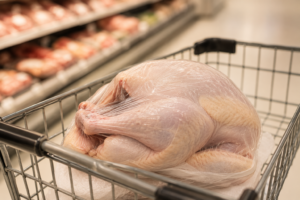 Frozen whole turkey in a grocery cart illustrating Thanksgiving turkey prices in 2026